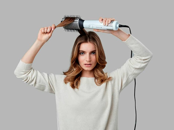 Mujer secándose el pelo con un cepillo moldeador de Remington