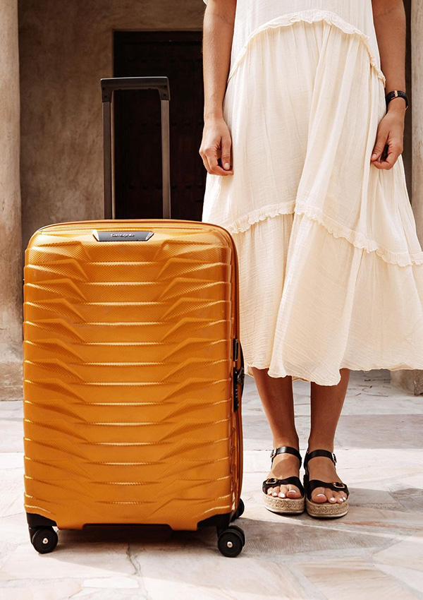 Mujer junto a una maleta naranja
